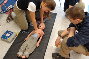 Students practicing CPR on a child manniken